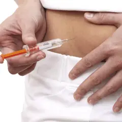 Osoba wykonuje zastrzyk podskórny z leku Clexane.
