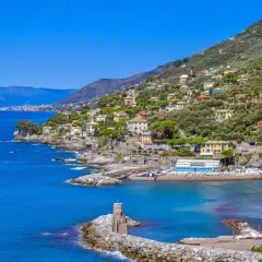 Vue pittoresque de la Riviera Italienne, avec des maisons colorées nichées sur une colline verdoyante surplombant la mer bleue.