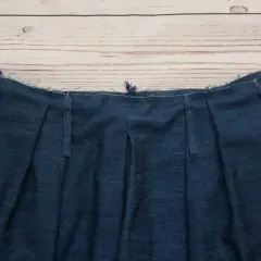 Close-up of a denim garment's waistband, showcasing various types of belt loops being prepared for sewing.