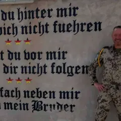 Ein Soldat der Bundeswehr steht vor einer Wand mit inspirierenden Bundeswehr Zitaten. "Gehe einfach neben mir und sei mein Bruder.