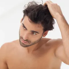 Hombre revisando su cabello en el espejo, parte de su rutina de cuidado del cabello hombre.