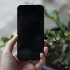 Dłoń trzyma czarny iPhone. Zastanawiasz się, jak wyłączyć iPhone bez dotyku?
