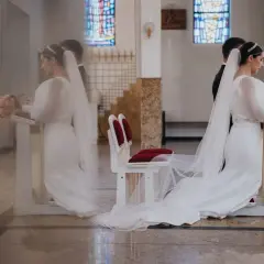 Panna młoda i pan młody klęczą przy ołtarzu. Wesele trwa, a oni przychodzą do siebie, by zawrzeć sakrament małżeństwa.