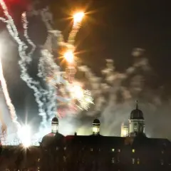Feuerwerk über Bergisch Gladbach. Farbenfrohe Raketen erleuchten den Nachthimmel über einem historischen Gebäude mit Kuppeln.