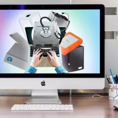 Festplatte wird nicht erkannt? Diagnose mit Stethoskop auf Laptop-Tastatur. Externe Laufwerke und Apple-Produkte im Hintergrund.