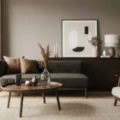 Ein Wohnzimmer mit dunklem Sofa, braunen Kissen und einem runden Holztisch. Die Frage, welche Farbe passt zu Schwarz, wird hier mit warmen Erdtönen beantwortet.