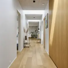 Un luminoso vano di disimpegno con pavimenti in legno chiaro, pareti bianche e armadi in legno.