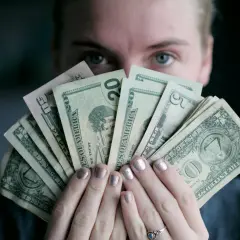 Osoba trzyma wachlarz banknotów dolarowych, zastanawiając się, czy paypal czy jest bezpieczny.