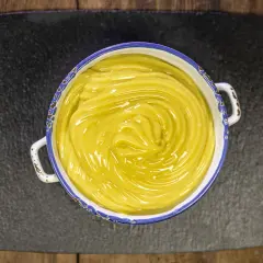 Una ciotola di cremosa crema pasticcera vegana, con un vortice lucido al centro, pronta per farcire dolci.