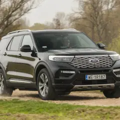 Czarny Ford Explorer 4x4 pokonuje piaszczystą drogę wśród drzew.