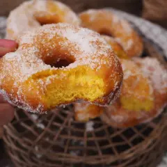 En hand håller en sockerdränkt munk, perfekt för ett hembakat donuts recept.