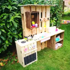 Kreative alte Weinkisten Deko Ideen: Kinderküche aus Paletten und Kisten im Garten, mit Spielzeuggeschirr und Sandkasten im Hintergrund.