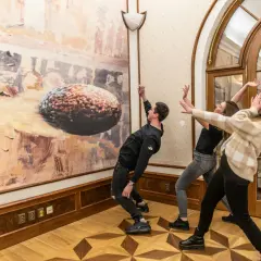 Trzech młodych ludzi w muzeum sztuki współczesnej w Pradze, wchodzących w interakcję z obrazem.