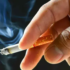 En hand håller en cigarett med rök som virvlar. Processen att fermentera tobak ger den dess karaktäristiska smak.