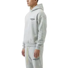 Szary komplet Essentials z kapturem i spodniami dresowymi. Zastanawiasz się, ile waży bluza Essentials? Jest lekka i wygodna.