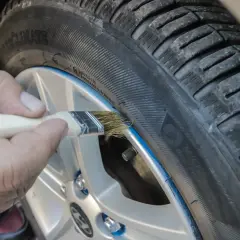 Ręka pędzlem maluje niebieską linię na oponie, nadając jej nowy wygląd. To nie jest zwykła guma w sprayu, to precyzyjne malowanie!