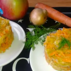 Dwie porcje surówki z kiszonej kapusty z jabłkiem, marchewką i koprem. Obok składniki: jabłko, cebula, marchewka.