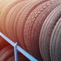 Rząd opon na niebieskim stojaku. Zastanawiasz się, jaki rozmiar opon do Renault Megane 3?
