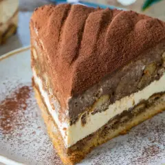 Pyszny kawałek ciasta cappuccino na biszkopcie, posypany kakao. Idealny przepis na deser.