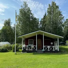 Rött hus med veranda och flaggstång i Stjärnsund. En växthus syns i bakgrunden.