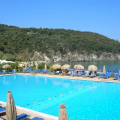 Piscina con lettini e ombrelloni, vista mare e collina verde. Informazioni su Negombo prezzi e orari per una vacanza rilassante.