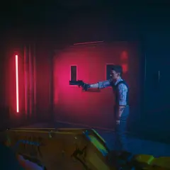 W dobra strone cyberpunk. Mężczyzna z pistoletem stoi przed drzwiami, a gracz celuje z żółtej broni.