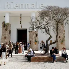 Ludzie spacerują przed budynkiem z napisem "la Biennale". Atmosfera jak na Biennale Wenecja 2026.
