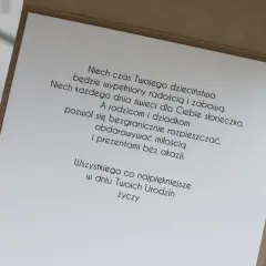 Wiersz z życzeniami "100 lat wszystkiego najlepszego z okazji urodzin" na kartce z brązowej tektury.