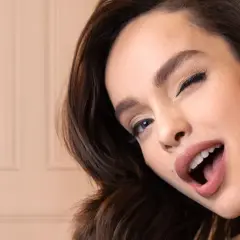 Uśmiechnięta kobieta prezentuje puder L'Oréal Infallible 24H Fresh Wear.