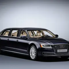 Ciemnogranatowy Audi A8L extended, luksusowa limuzyna z jasnym wnętrzem, prezentuje się elegancko na tle gradientu.