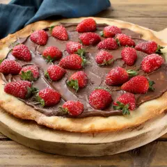 Słodka pizza z truskawkami i kremem czekoladowym na drewnianej desce. Idealna na deser!
