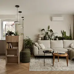 Przytulny szary salon z dużą ilością zielonych roślin, jasną kanapą i drewnianymi meblami.