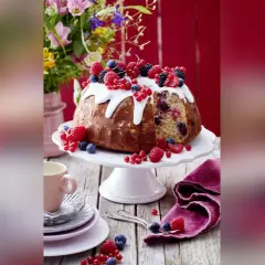 Ein köstlicher Gugelhupf mit Mandeln, Beeren und Zuckerguss, dekoriert mit frischen Früchten.