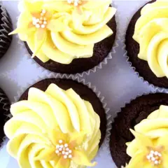 Chokladmuffins med gul frosting och blomsterdekoration. En härlig syn av frosting muffins som ser aptitliga ut.