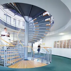 Moderne Wendeltreppe in einer Klinik mit zwei Personen, die sie benutzen.