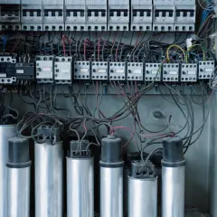 Wnętrze rozdzielnicy elektrycznej z kondensatorami i stycznikami, kluczowe dla poprawy współczynnika mocy cos fi.