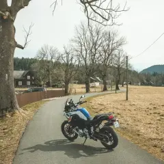 Motocykl na drodze w Czechach, wśród domków i drzew.