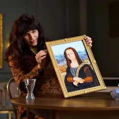 Frau hält ein detailreiches Lego-Mona-Lisa-Bild hoch.