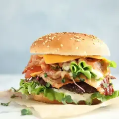 Wiesmaczny burger z bekonem, serem i świeżymi warzywami, idealny na szybki posiłek.
