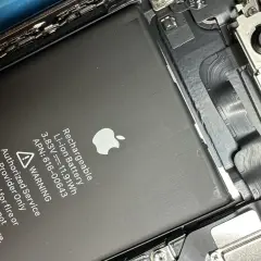Wymiana baterii w iPhone 11. Widoczna bateria Li-ion z oznaczeniami i ostrzeżeniami.