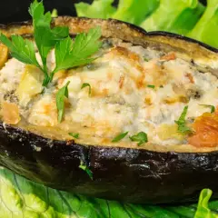 Melanzane ripiene di carne al forno, un piatto gustoso e colorato, servito su un letto di lattuga fresca.