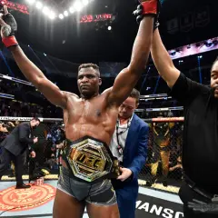 En segerrik UFC-mästare, med bälte och armarna i luften, firar som en riktig sumo brottare.