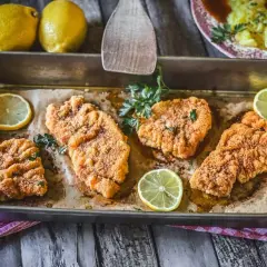 Vier goldbraune Schnitzel im Backofen, garniert mit Petersilie und Zitronenscheiben. Ein Genuss für Augen und Gaumen!