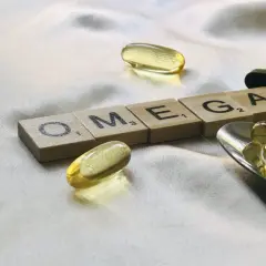 Capsule di olio di pesce e tessere con la scritta OMEGA. Chissà dopo quanto tempo fanno effetto gli omega-3 per il benessere.