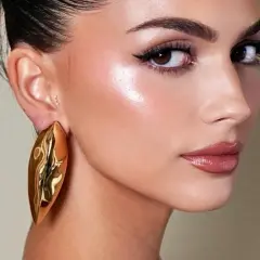 Rostro con maquillaje radiante, destacando el uso de iluminador en barra para un brillo natural.