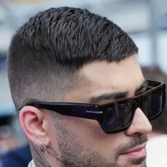Nahaufnahme eines Mannes mit kurz geschnittenem, dunklem Haar und Sonnenbrille. Sein moderner herren haarschnitt ist perfekt gestylt.