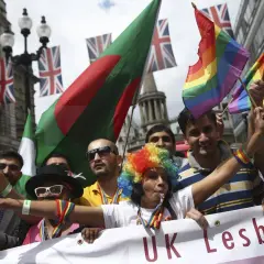 People wave rainbow and national flags at a pride parade, showing why understanding diversity is important for unity and celebration.