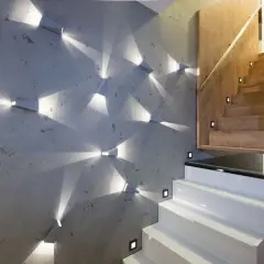 Moderne Wandgestaltung mit geometrischen Spots, die Lichtmuster auf Beton werfen. Perfekte Wand-Inspo für einen stilvollen Treppenaufgang.