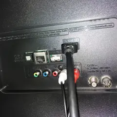 Tył telewizora z podłączonymi kablami HDMI, USB, LAN i audio.