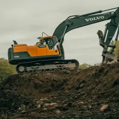Duża koparka Volvo pracuje na budowie. Zastanawiasz się, ile zarabia operator koparki?